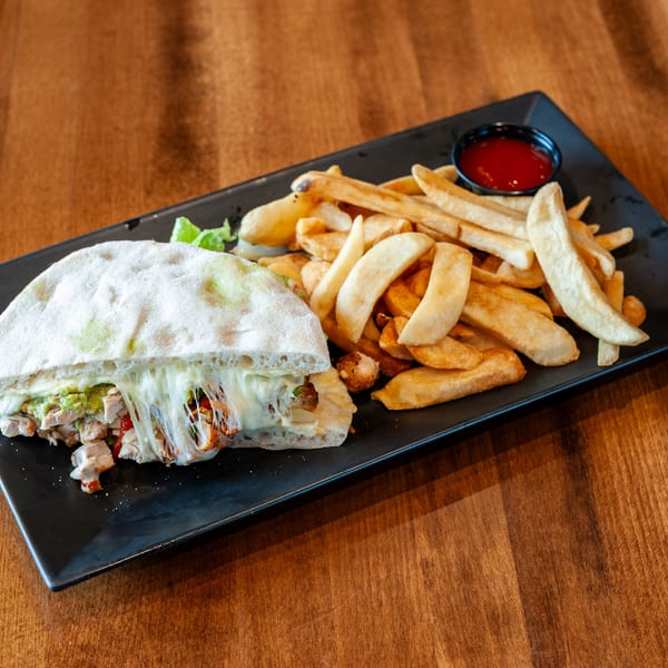 A chicken quesadilla with melted cheese and guacamole, served with golden french fries and ketchup.